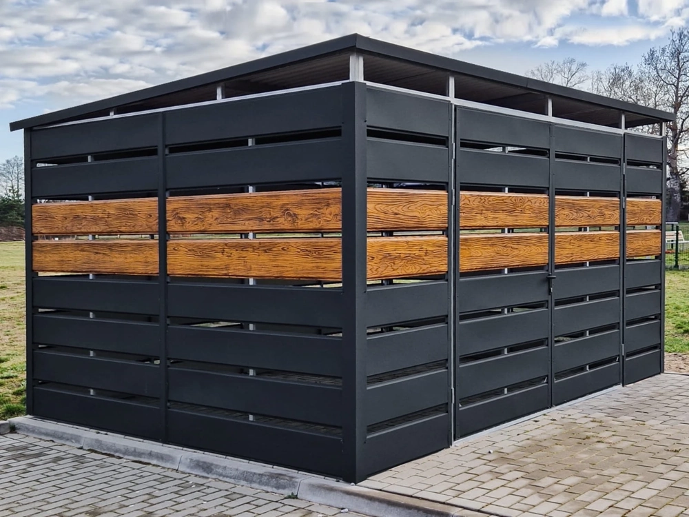 Czarna wiata śmietnikowa z drewnianymi panelami na kostce brukowej